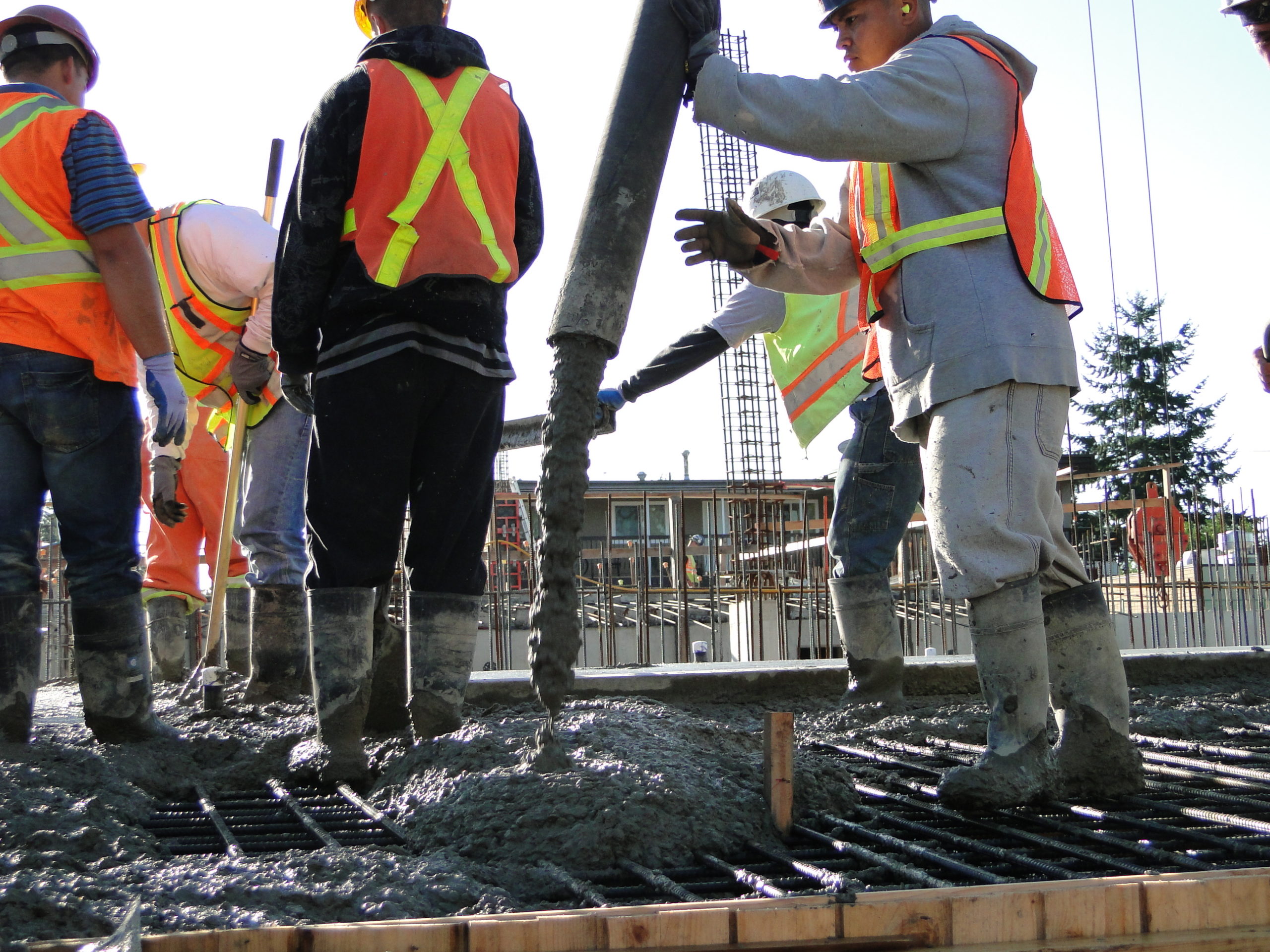 A group of construction workers are working on pouring concrete at a worksite.