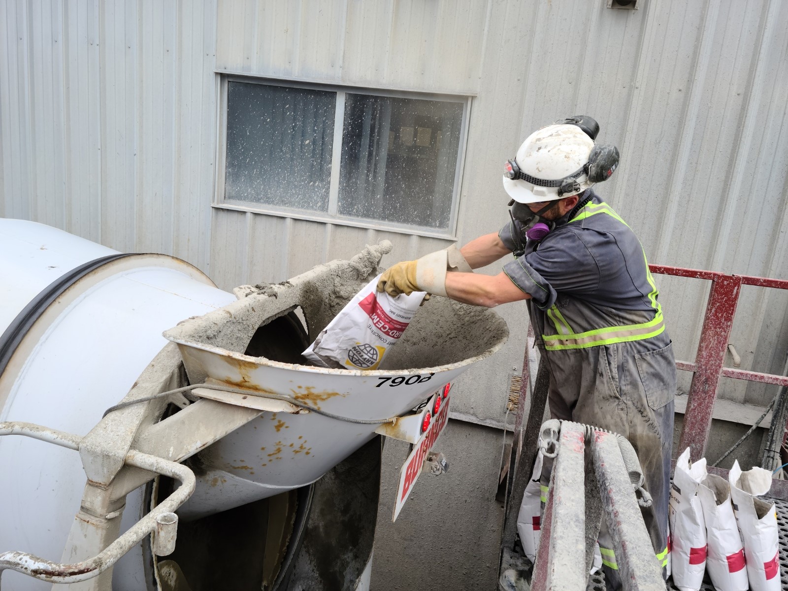 A construction worker is adding Hard-Cem into his concrete mix during batching.